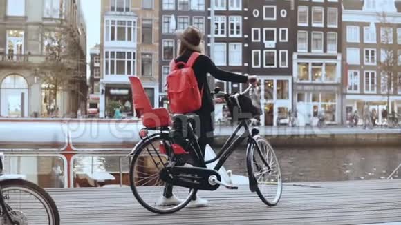 骑自行车的女性站在热闹的河堤上实时后视图欧洲女旅行者荷兰阿姆斯特丹视频的预览图