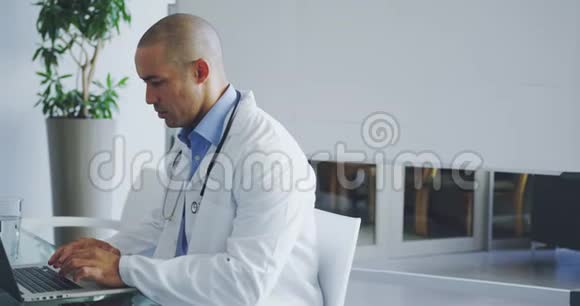 男性医生在办公室办公桌上使用笔记本电脑视频的预览图