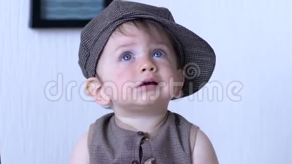 戴帽子的时髦孩子侧着头看着背景白墙视频的预览图