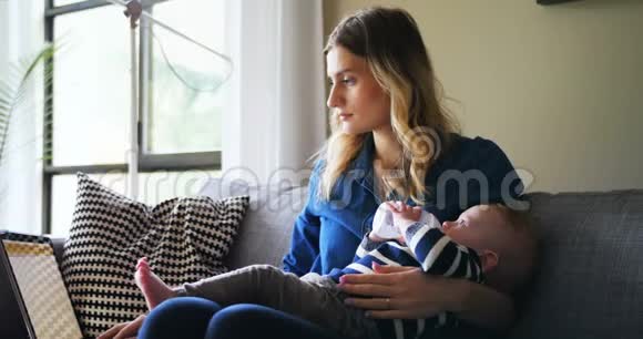 母亲在给婴儿喂奶时使用笔记本电脑视频的预览图