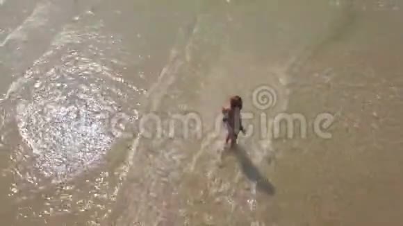 年轻女子穿着比基尼在夏季海滩上漫步在透明的海水无人机视野中从上面幸福的女人视频的预览图