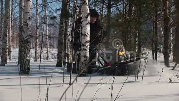 勇敢的人在冬季森林中的树木之间的深雪堆上驾驶微型雪车视频的预览图