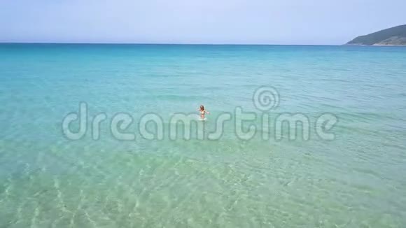 快乐的女人享受海水在夏季海滩无人机视野女子乘坐绿松石海水在天堂海滩鸟瞰视频的预览图