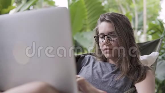 自由职业者坐在吊床上的女士喜欢笔记本电脑视频的预览图