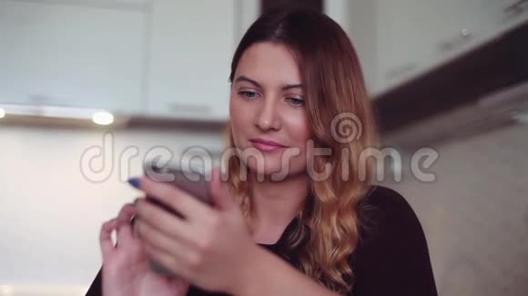 一个漂亮的年轻女孩用智能手机在线聊天家风视频的预览图