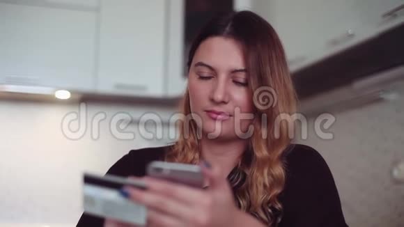 网上购物一个漂亮的年轻女孩把她的信用卡信息输入智能手机进行购买高清高清视频的预览图