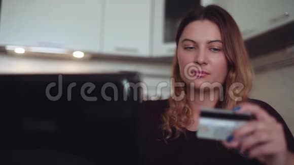 美丽的年轻女性网上银行使用移动电脑和信用卡有一个良好的心情家庭风格视频的预览图