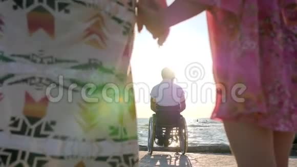 轮椅上的跛行与家人母亲和女儿保持手的背景父亲坐在轮椅附近的水视频的预览图