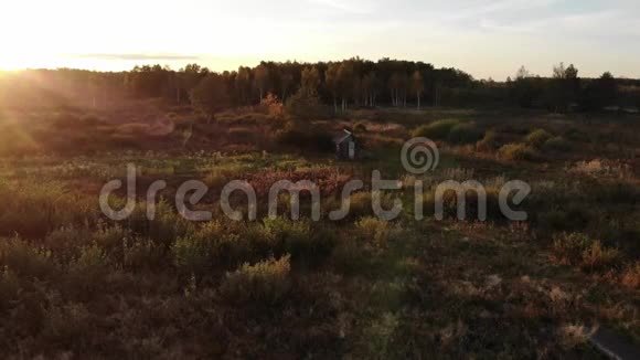 秋季傍晚精彩日落自然之美镜头耀斑自然效果草地中央的木屋视频的预览图