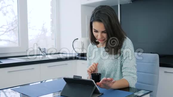早上好可爱的女性在桌子上喝咖啡和平板电脑视频的预览图