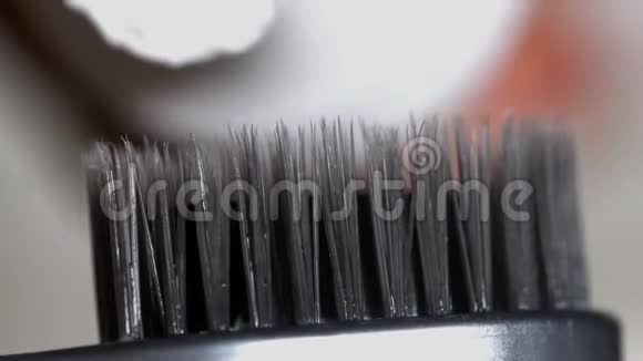在黑色牙刷上涂抹牙膏媒体在牙刷特写上涂抹牙膏视频的预览图