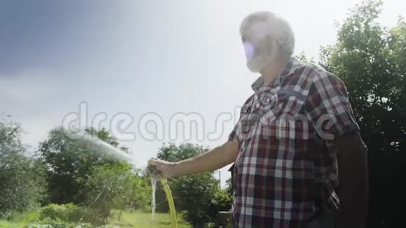 长者用水管浇灌夏日花园视频的预览图