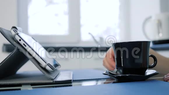 女性手与勺子混合茶在杯子和点击在平板电脑上的不集中的背景视频的预览图
