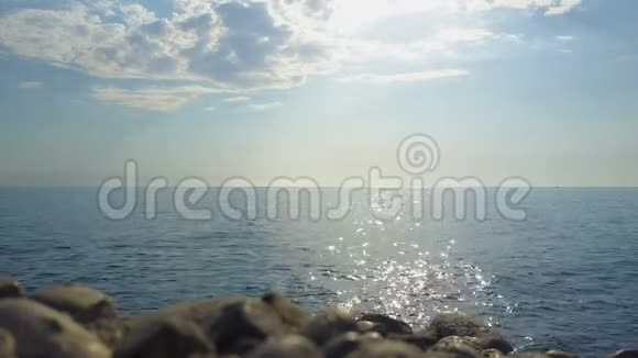 平静的大海温暖的晴天太阳在地平线上前面有石头视频的预览图