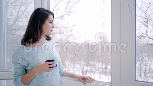 在度假时女人在敞开的窗户附近呼吸新鲜空气喝着芬芳的茶视频的预览图