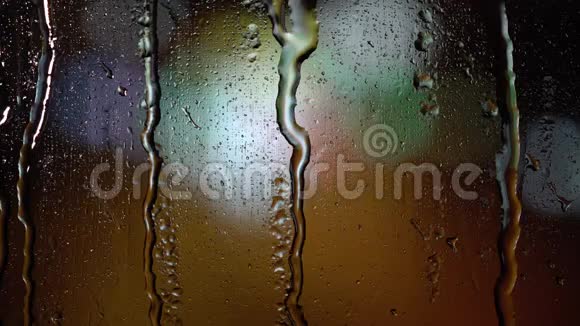 晚上在玻璃上下一滴雨模糊的背景视频的预览图