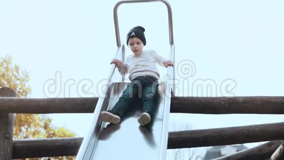 从公园滑梯上下来的小欧洲男孩快乐无忧无虑的男孩子戴着帽子在冒险公园操场上玩得很开心视频的预览图