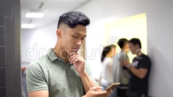 亚洲帅哥在智能手机上尝试新应用脸很严肃视频的预览图