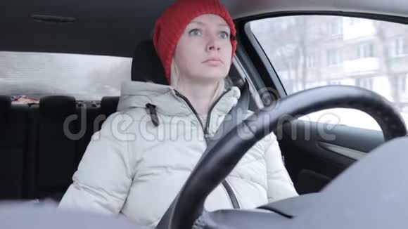 穿着冬装戴着橙色针织帽子的女人在冬道上开车视频的预览图