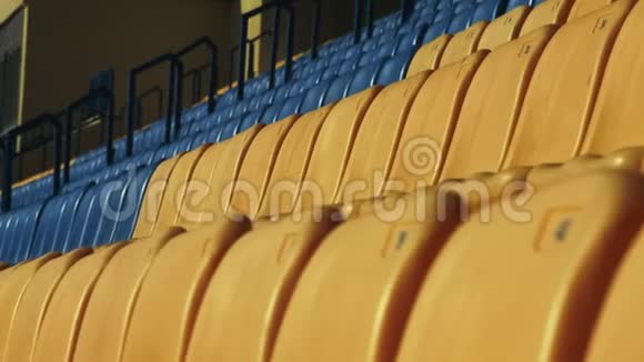 在足球场上空着黄色和蓝色的座位把一排塑料椅子视频的预览图
