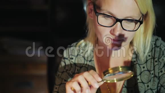 一个戴眼镜的女人通过放大镜看东西仔细研究视频的预览图