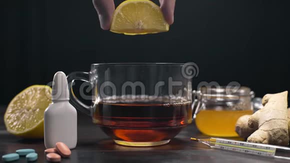 柠檬被挤到维生素红茶与生姜柠檬茶和蜂蜜站在桌子上与药丸和视频的预览图