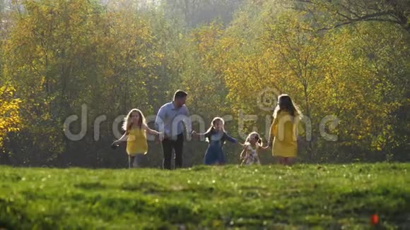 快乐的年轻家庭和他们的小狗在秋天的公园里奔跑视频的预览图