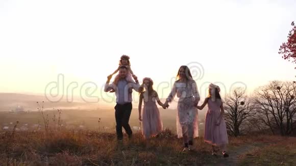 幸福的年轻豪华打扮的家庭在秋天公园散步在日落视频的预览图