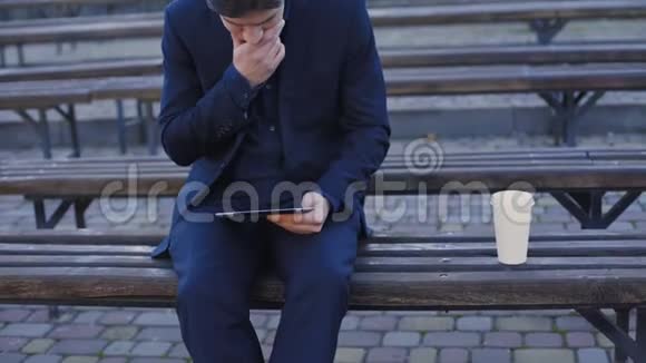 帅哥坐在长凳上用平板电脑和智能手机4K视频的预览图