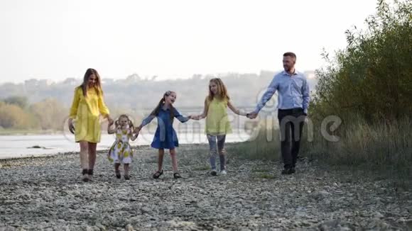 幸福的年轻家庭走在河边视频的预览图