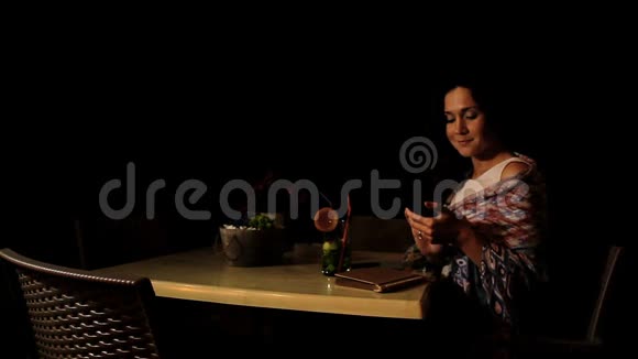 快乐的黑发女孩在海滩咖啡馆和朋友打电话放松的夜晚视频的预览图