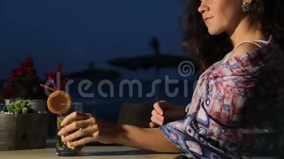 女孩在海滩咖啡馆喝鸡尾酒在日记里写回忆度假视频的预览图