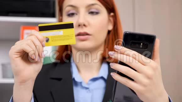 女商人看着她的信用卡介绍了智能手机上的数据视频的预览图