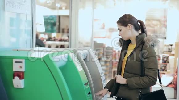 年轻女子使用自动取款机购物中心的女孩开着提款机有一些钱财务概念视频的预览图