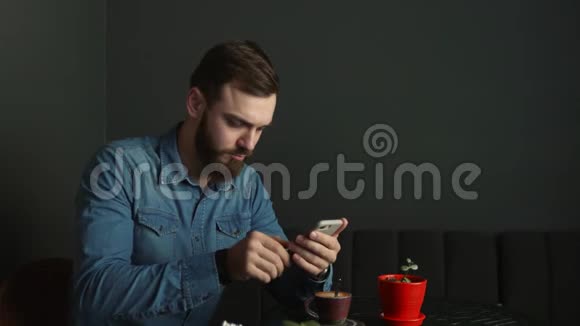 咖啡馆里留着胡子的年轻人的肖像蓝色衬衫男士写留言视频的预览图
