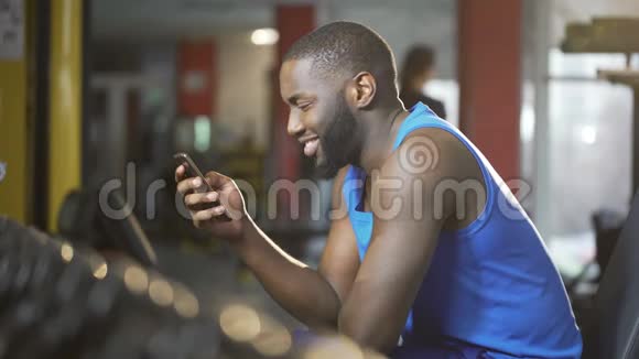 年轻人微笑着在智能手机上打字锻炼时休息视频的预览图