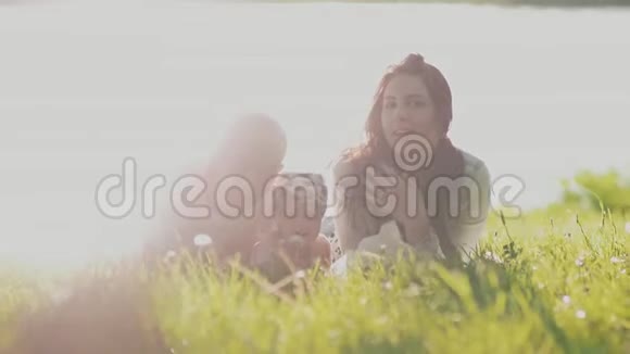 年轻快乐的父母和一个小可爱的女儿躺在夏日阳光明媚的草地上我爱你视频的预览图