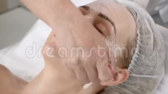 美容诊所年轻女人有专业的面部手术美容师用刷子在女性脸上涂面膜脸面视频的预览图