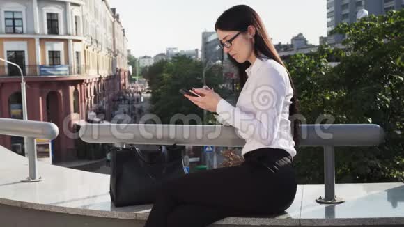 商务女性在城市街头工作时使用智能手机视频的预览图