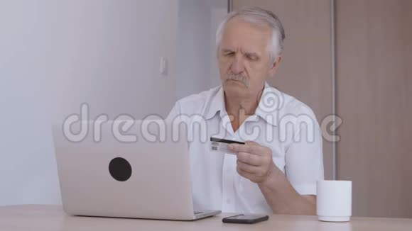 老人在家里用笔记本电脑上网打信用卡号码视频的预览图