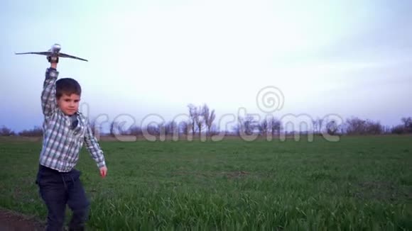 手拿玩具飞机的孩子在野外和天空的背景下在户外跑步视频的预览图