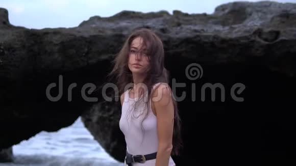 日落时分身穿泳装在悬崖和海洋附近拍照的年轻女人视频的预览图