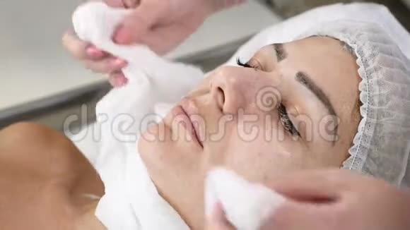 美容诊所年轻女人有专业的面部手术美容师用毛巾将女性客户的脸暖和起来视频的预览图