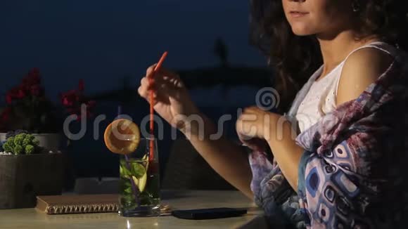 布鲁内特女士在海滩咖啡馆休息喝鸡尾酒享受夜晚视频的预览图