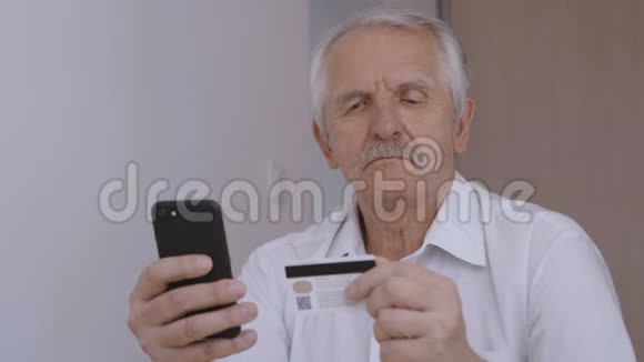 老人在家用智能手机用信用卡在线购物网上银行手机应用视频的预览图