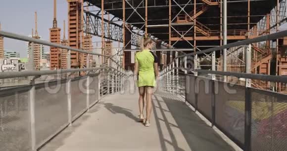 年轻的金发女子在健身穿着热身在人行道上跑步训练夏日阳光明媚工业绿色城市视频的预览图