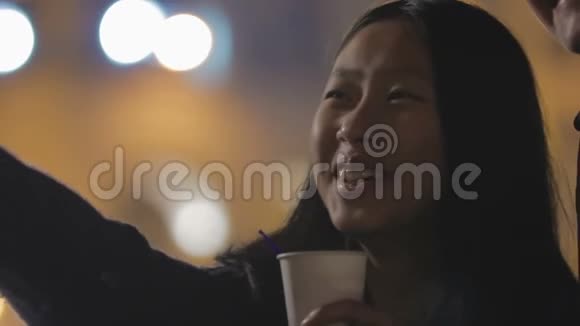 微笑的亚洲女孩站在街上和男朋友一起看灯光秀视频的预览图