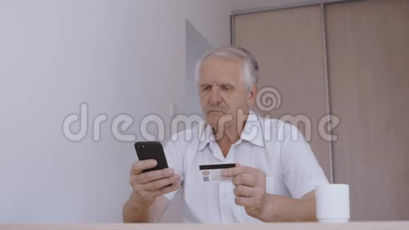 老人在家用智能手机用信用卡在线购物网上银行手机应用视频的预览图