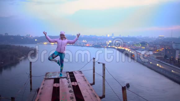 勇敢的年轻女子站在桥上的瑜伽姿势危险的爱好视频的预览图