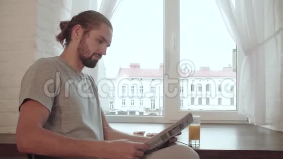 早餐男人阅读报纸喝果汁和吃食物视频的预览图